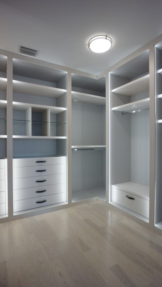 Medium sized modern gender neutral walk-in wardrobe in Miami with flat-panel cabinets, white cabinets and light hardwood flooring.