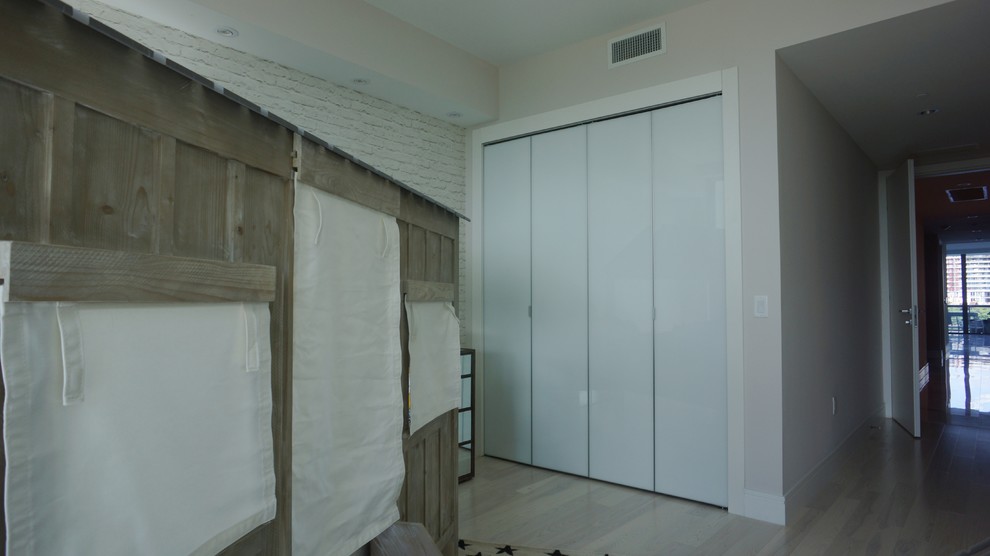 Ejemplo de armario vestidor unisex minimalista de tamaño medio con armarios con paneles lisos, puertas de armario blancas y suelo de madera clara