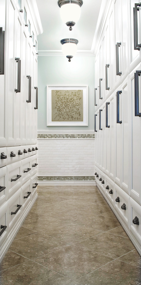 Exempel på ett stort klassiskt omklädningsrum för könsneutrala, med kalkstensgolv, luckor med infälld panel, vita skåp och beiget golv