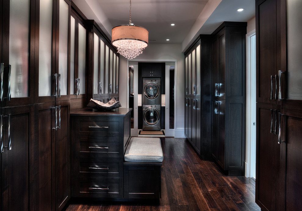 Large eclectic gender neutral walk-in wardrobe in Other with glass-front cabinets, dark wood cabinets and medium hardwood flooring.