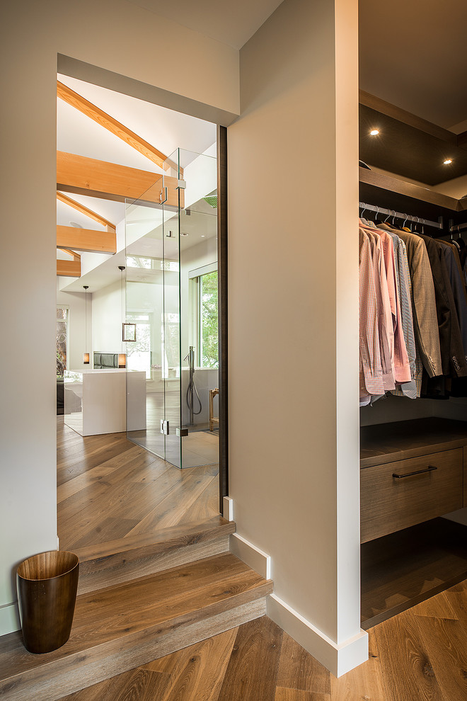 Exemple d'un dressing room tendance en bois foncé de taille moyenne pour un homme avec un placard à porte plane et un sol en bois brun.