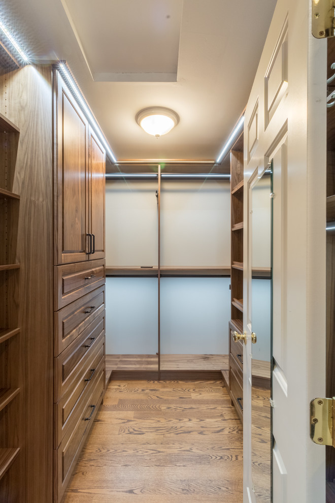 Medium sized classic walk-in wardrobe for men in Minneapolis with raised-panel cabinets, medium wood cabinets and medium hardwood flooring.