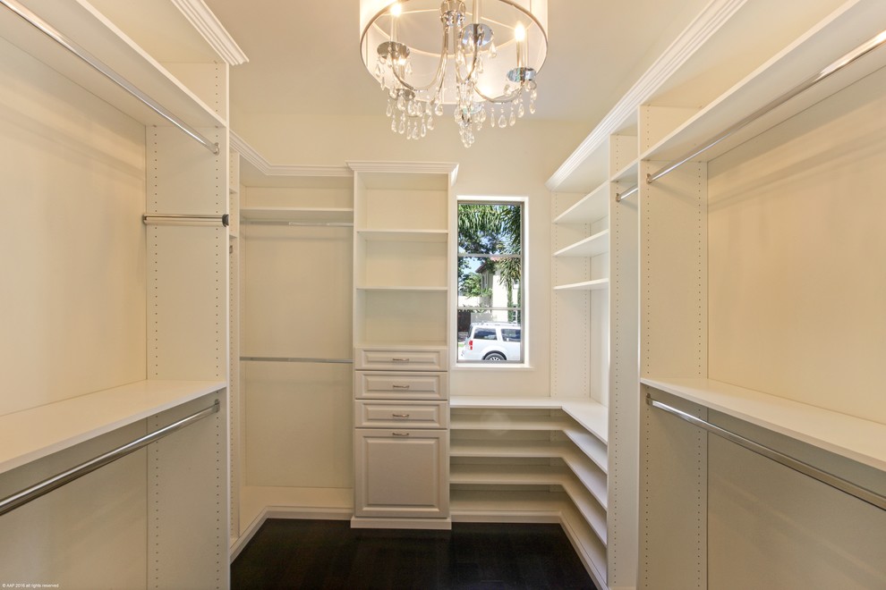 This is an example of a medium sized mediterranean walk-in wardrobe for women in Miami with open cabinets, white cabinets and dark hardwood flooring.