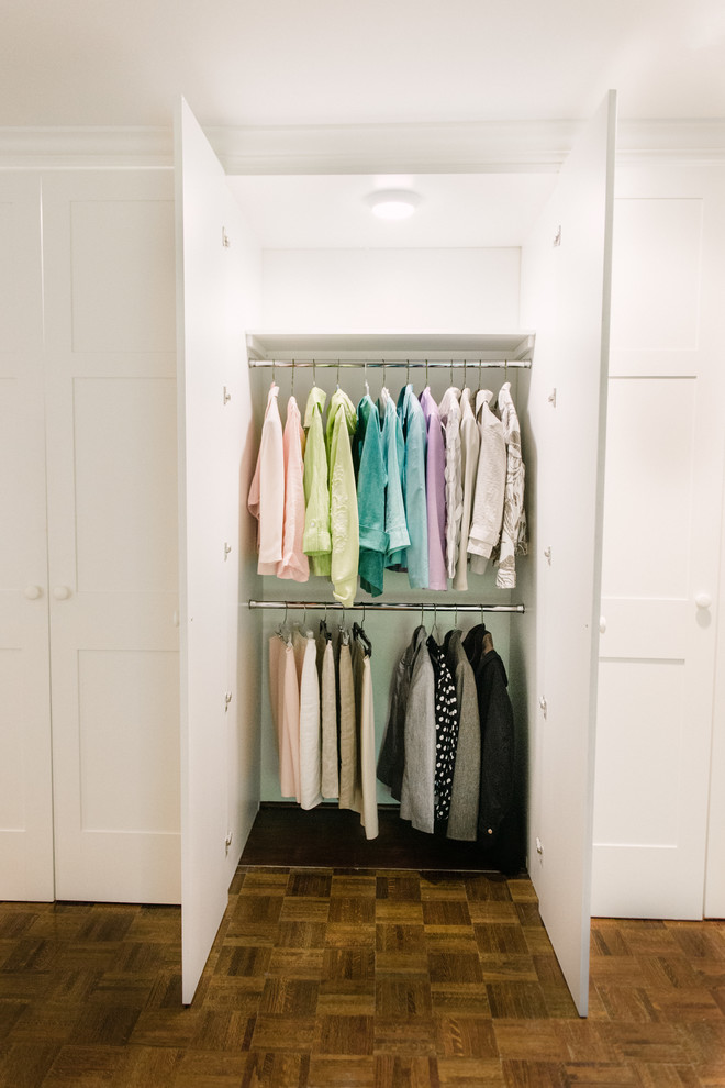 Inspiration for a medium sized classic gender neutral standard wardrobe in Birmingham with flat-panel cabinets, white cabinets and medium hardwood flooring.