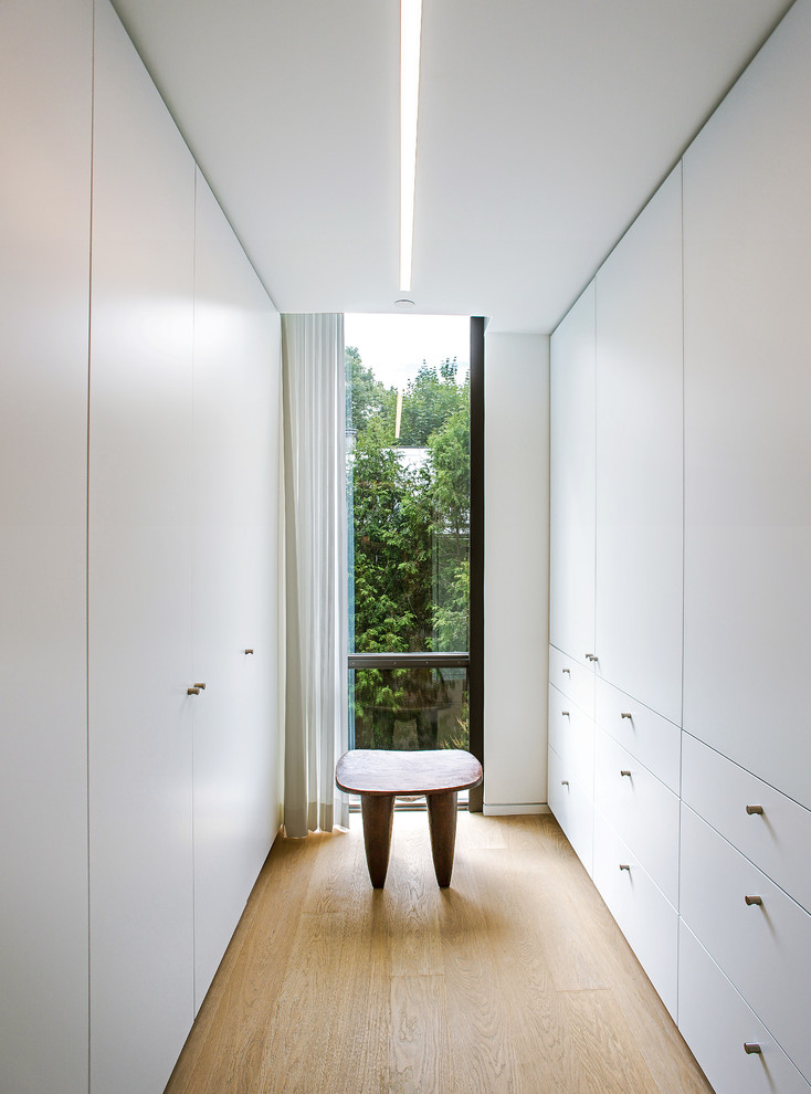 Cette photo montre un grand dressing room tendance neutre avec un placard à porte plane, des portes de placard blanches, parquet clair et un sol beige.