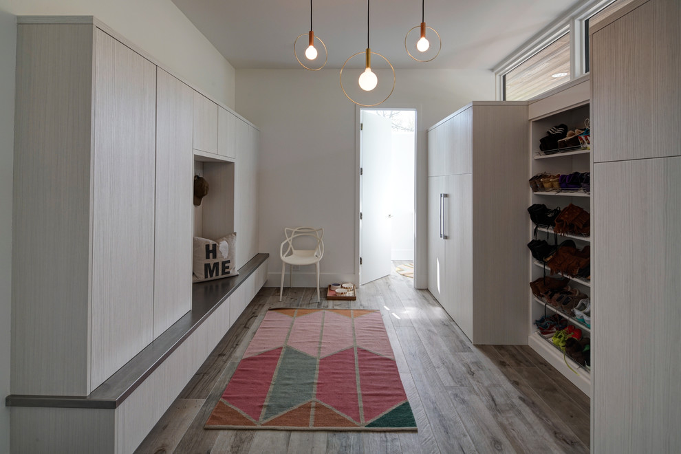 Example of a large trendy gender-neutral medium tone wood floor and brown floor walk-in closet design in Chicago with flat-panel cabinets and light wood cabinets