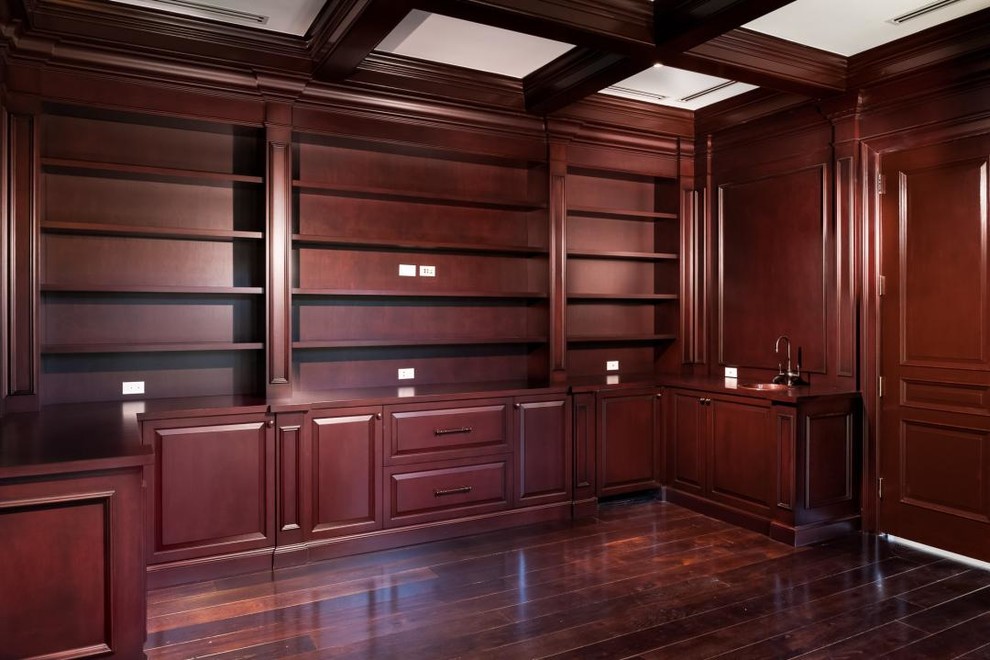 Ejemplo de vestidor unisex clásico de tamaño medio con armarios con paneles con relieve, puertas de armario de madera en tonos medios y suelo de madera oscura