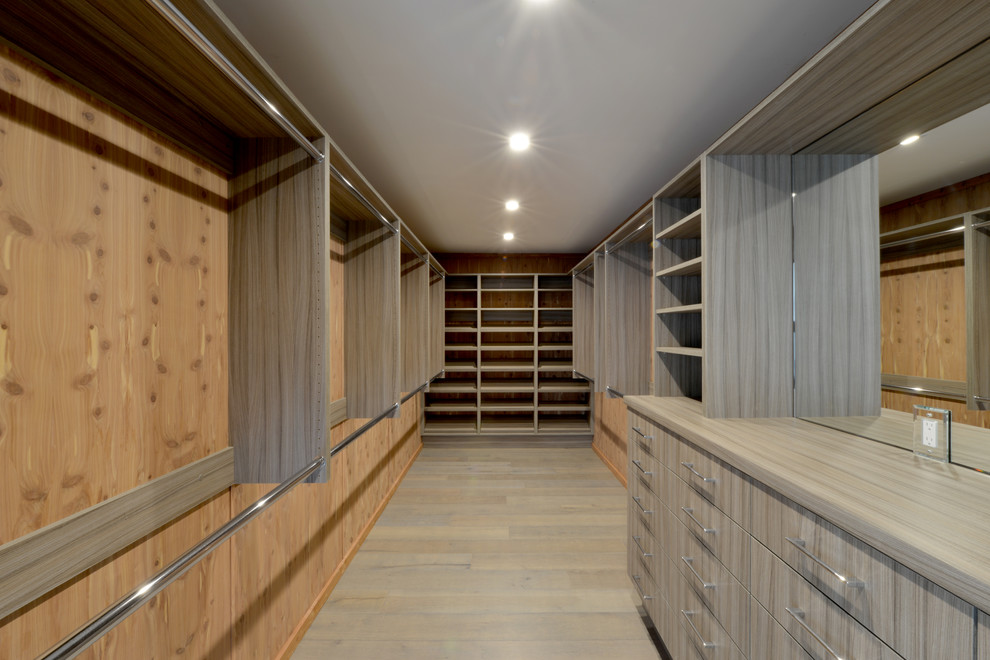 Ispirazione per un'ampia cabina armadio unisex minimalista con ante lisce, ante in legno chiaro e parquet chiaro
