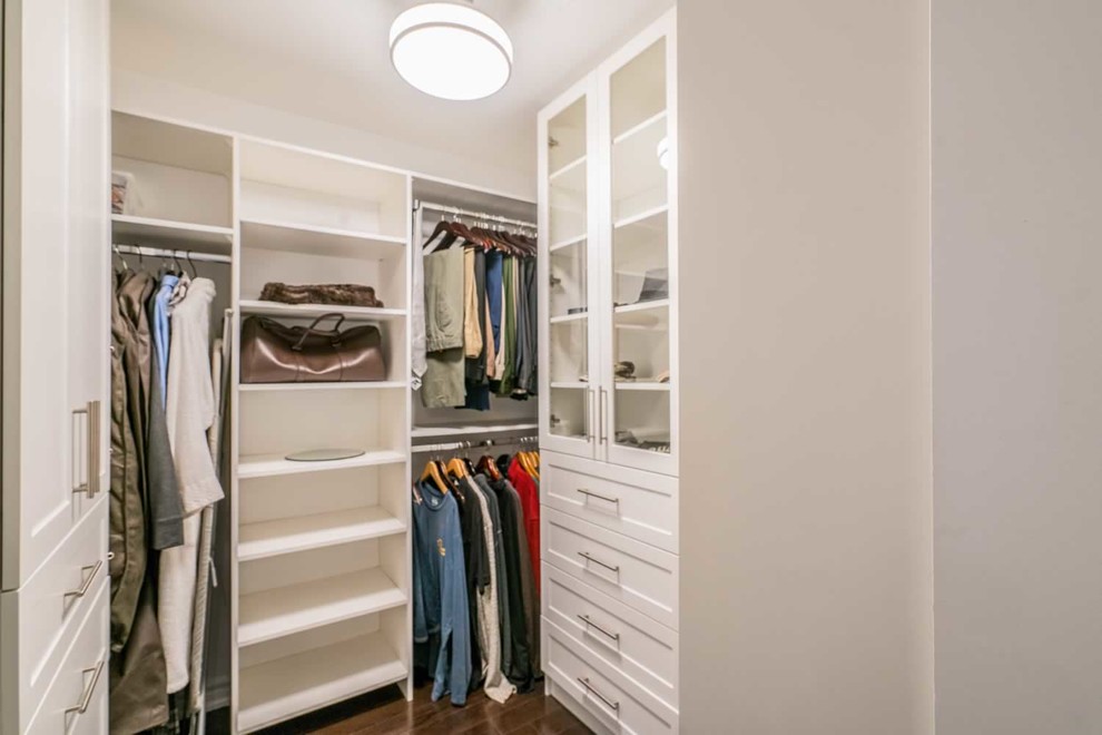 Inspiration for a small classic gender neutral walk-in wardrobe in Toronto with glass-front cabinets, white cabinets, dark hardwood flooring and brown floors.