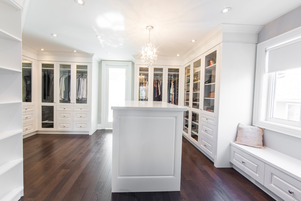 Foto de armario vestidor unisex tradicional renovado grande con armarios con paneles con relieve, puertas de armario blancas y suelo de madera oscura