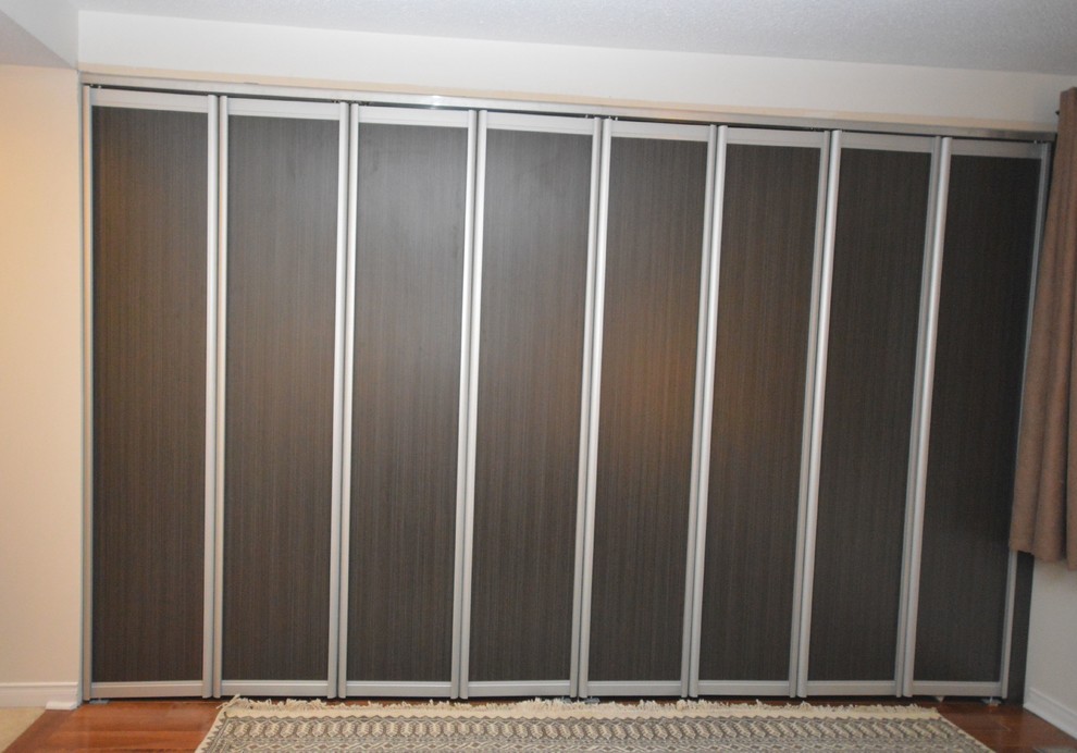 Exemple d'un petit placard dressing tendance pour un homme avec un placard avec porte à panneau surélevé, des portes de placard marrons et un sol en bois brun.