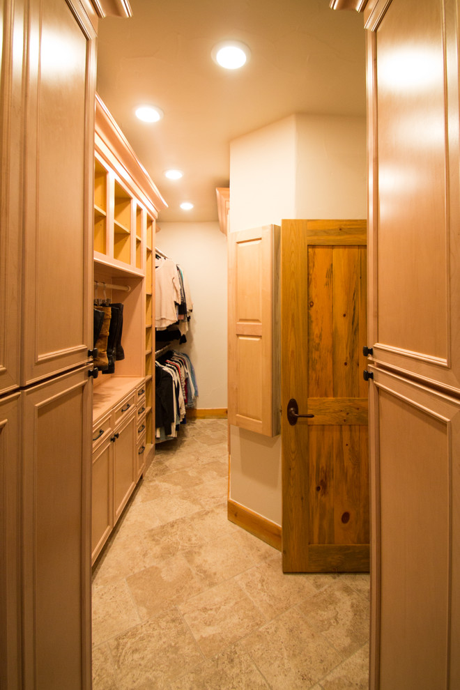 Diseño de armario vestidor unisex clásico grande con armarios con paneles con relieve, puertas de armario de madera clara, suelo de travertino y suelo beige