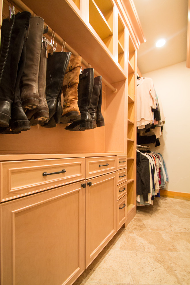 Large classic gender neutral walk-in wardrobe in Denver with raised-panel cabinets, light wood cabinets, travertine flooring and beige floors.