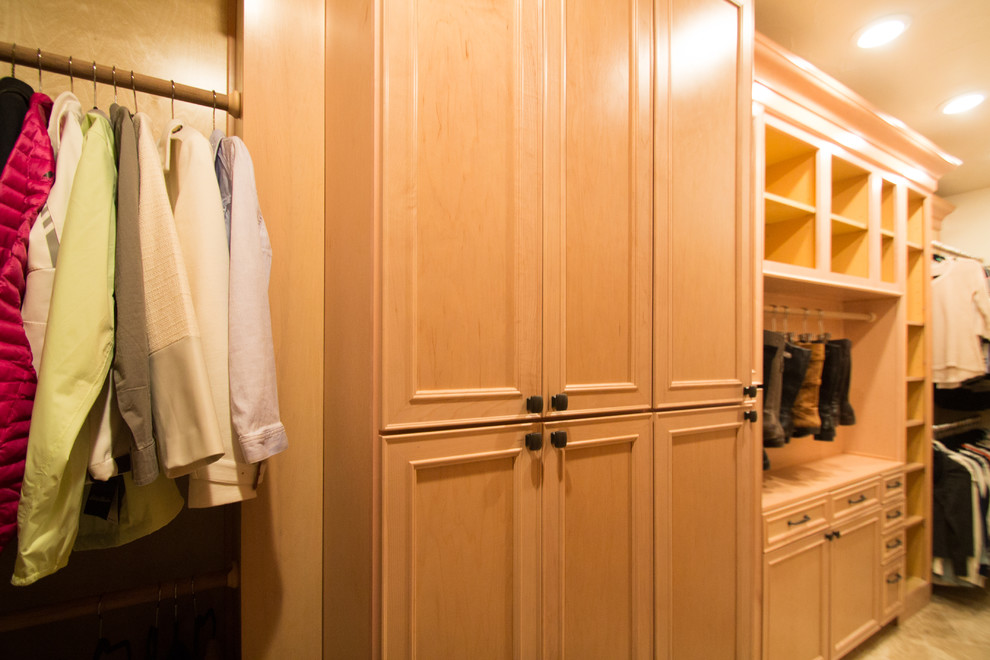 Large traditional gender neutral walk-in wardrobe in Denver with raised-panel cabinets, light wood cabinets, travertine flooring and beige floors.