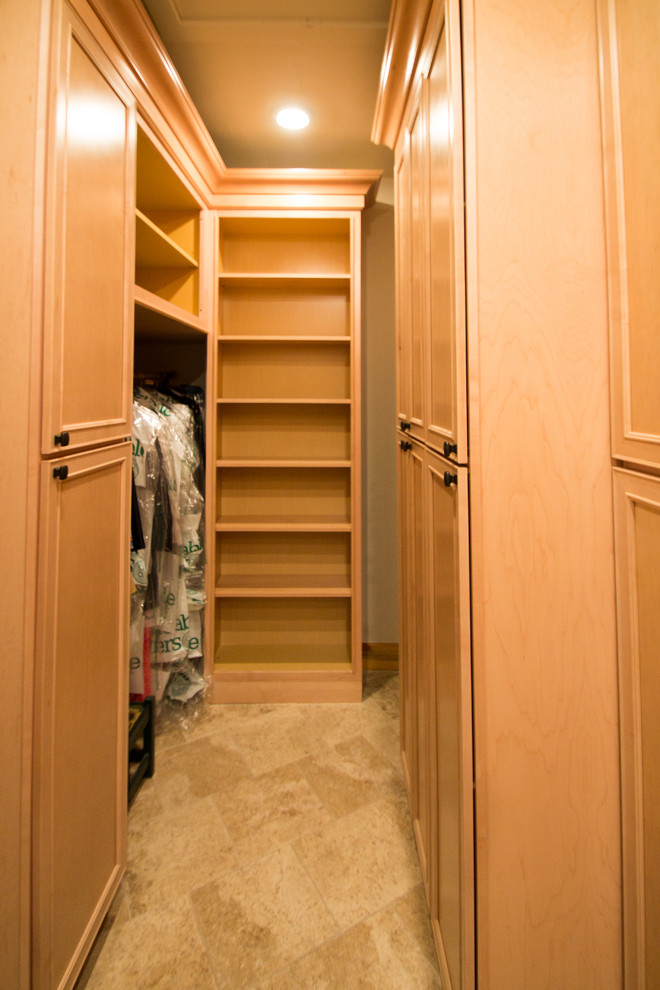 Ejemplo de armario vestidor unisex clásico grande con armarios con paneles con relieve, puertas de armario de madera clara, suelo de travertino y suelo beige