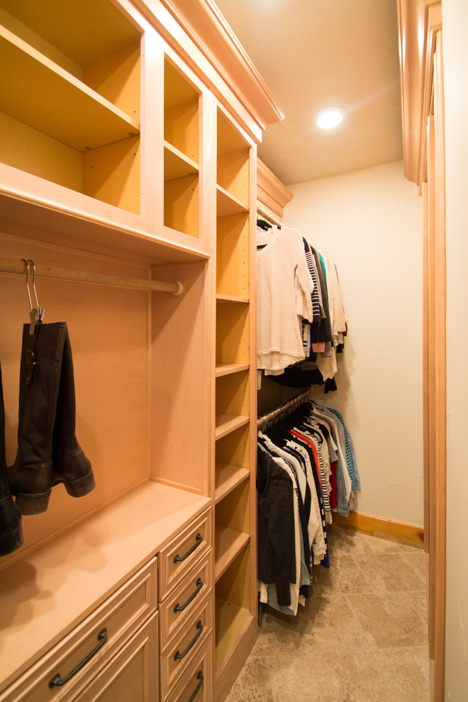 Diseño de armario vestidor unisex tradicional grande con armarios con paneles con relieve, puertas de armario de madera clara, suelo de travertino y suelo beige