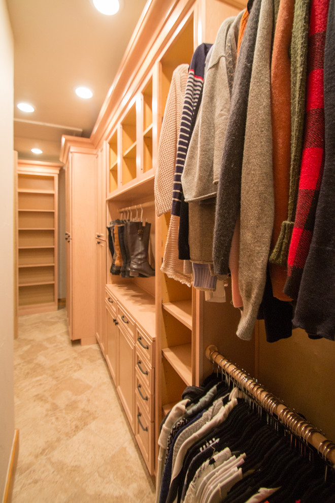 Large classic gender neutral walk-in wardrobe in Denver with raised-panel cabinets, light wood cabinets, travertine flooring and beige floors.
