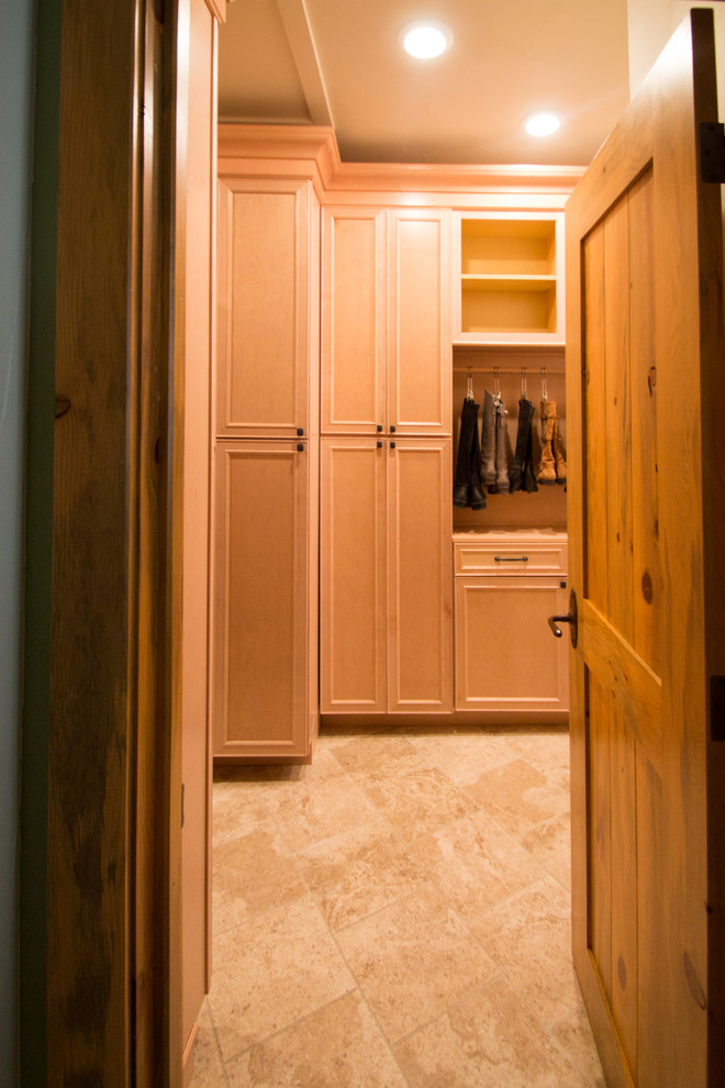 This is an example of a large traditional gender neutral walk-in wardrobe in Denver with raised-panel cabinets, light wood cabinets, travertine flooring and beige floors.