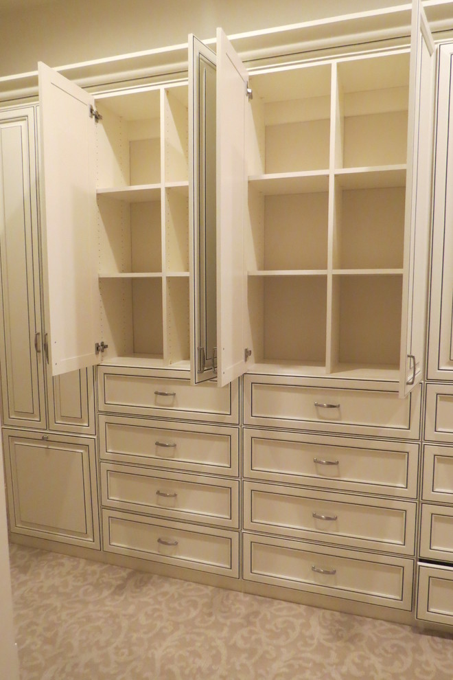 Imagen de armario vestidor de mujer clásico grande con armarios con paneles con relieve, puertas de armario con efecto envejecido y moqueta