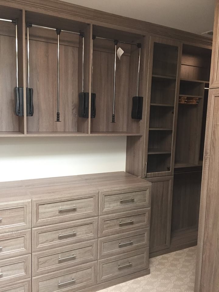 This is an example of a medium sized contemporary gender neutral walk-in wardrobe in Atlanta with recessed-panel cabinets, light wood cabinets, carpet and beige floors.