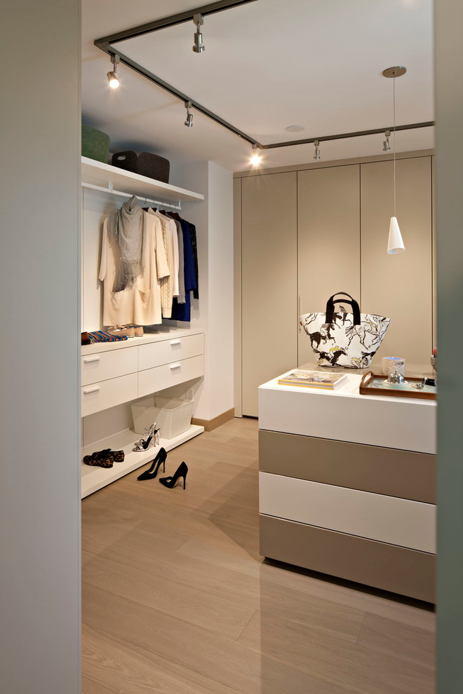Ejemplo de vestidor de hombre minimalista de tamaño medio con armarios con paneles lisos, puertas de armario beige, suelo de madera clara y suelo beige
