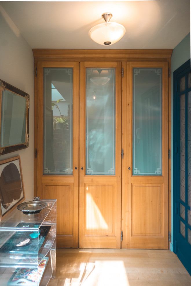 Ejemplo de armario y vestidor unisex vintage con a medida, armarios tipo vitrina y puertas de armario de madera clara