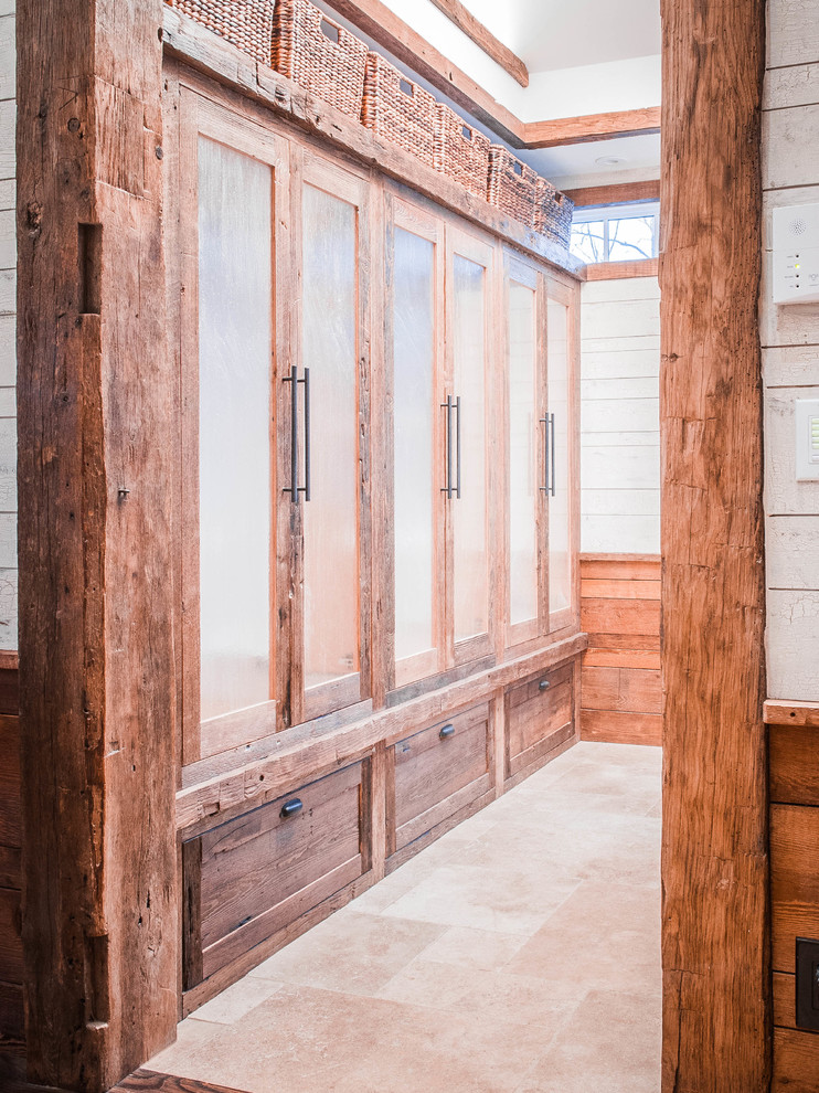 Aménagement d'un dressing campagne en bois vieilli neutre avec un placard à porte vitrée.