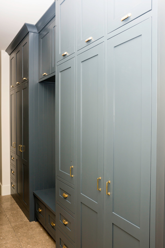 На фото: гардеробная комната среднего размера, унисекс в стиле неоклассика (современная классика) с фасадами в стиле шейкер, синими фасадами, полом из травертина и коричневым полом