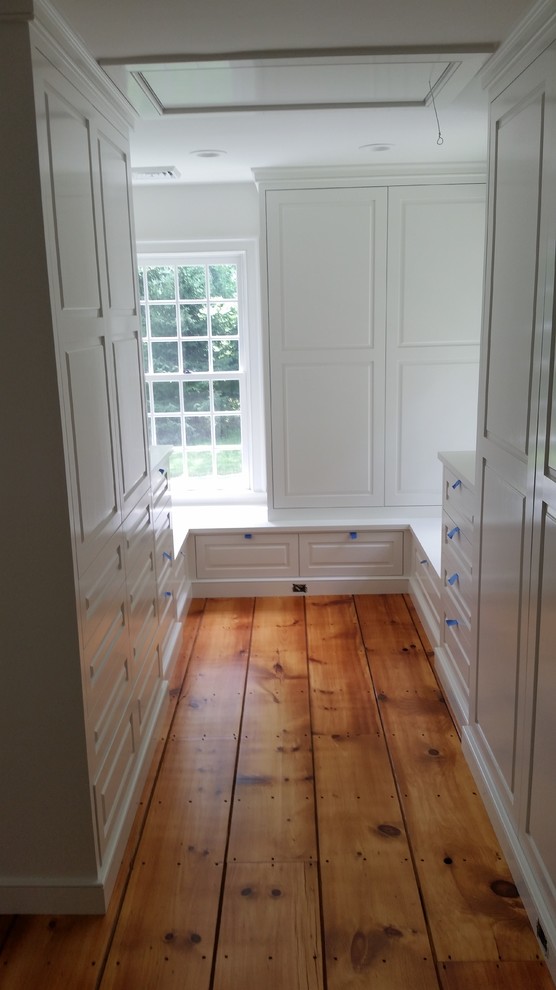 Imagen de armario vestidor unisex campestre grande con puertas de armario blancas y suelo de madera en tonos medios