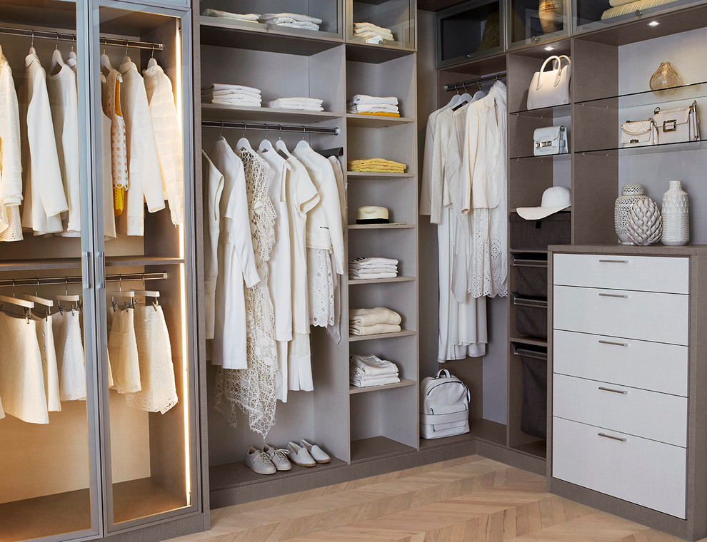 Large modern walk-in wardrobe for women in Nashville with light hardwood flooring, flat-panel cabinets and beige cabinets.