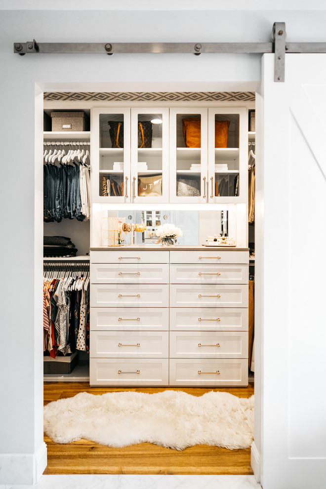 Modelo de armario vestidor unisex tradicional renovado de tamaño medio con armarios estilo shaker, puertas de armario blancas, suelo de madera en tonos medios y suelo marrón