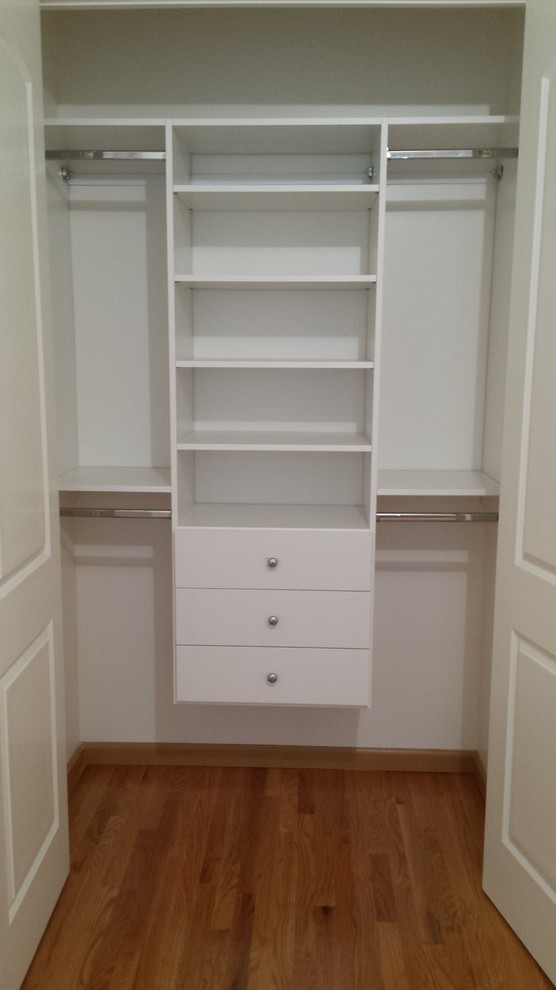 Ejemplo de armario unisex contemporáneo de tamaño medio con armarios con paneles lisos, puertas de armario blancas y suelo de madera clara