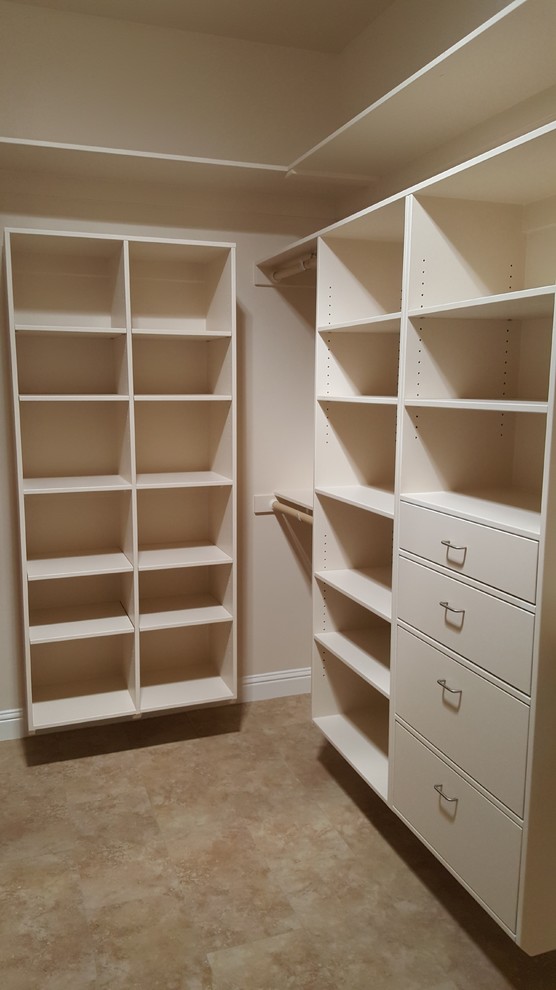 This is an example of a large contemporary gender neutral walk-in wardrobe in Sacramento with flat-panel cabinets, white cabinets and travertine flooring.