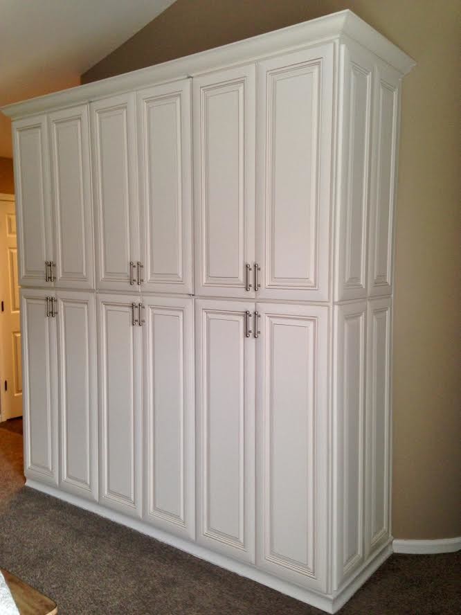 Immagine di un piccolo armadio o armadio a muro unisex tradizionale con ante con bugna sagomata, ante bianche, moquette e pavimento beige