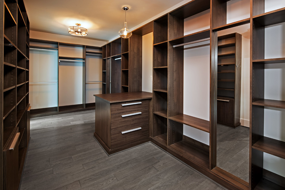 Imagen de armario vestidor unisex moderno extra grande con armarios con paneles lisos, puertas de armario de madera oscura, suelo de madera clara y suelo marrón