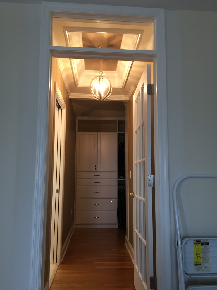 Foto de armario vestidor unisex clásico de tamaño medio con armarios con paneles empotrados, puertas de armario blancas y suelo de madera en tonos medios