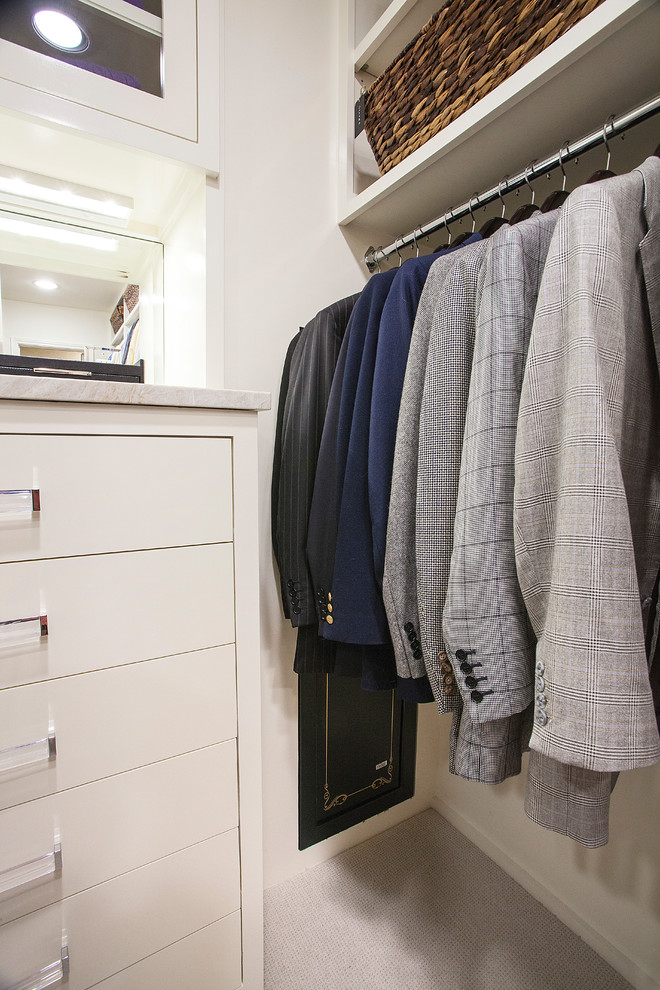 Diseño de armario vestidor de hombre clásico grande con armarios con paneles lisos, puertas de armario blancas, moqueta y suelo beige