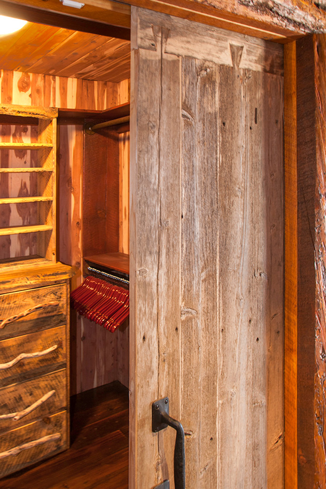 ウィチタにある中くらいなラスティックスタイルのおしゃれなウォークインクローゼット (フラットパネル扉のキャビネット、ヴィンテージ仕上げキャビネット、濃色無垢フローリング) の写真
