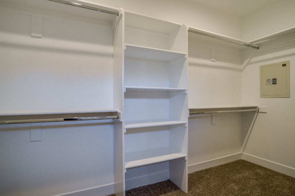 Photo of a gender neutral walk-in wardrobe in Portland with open cabinets, white cabinets, carpet and beige floors.