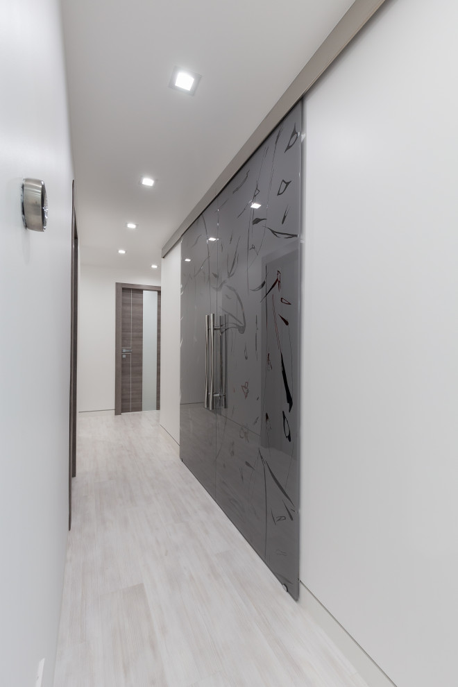 Cette image montre un placard dressing minimaliste de taille moyenne et neutre avec un placard à porte vitrée, des portes de placard grises, sol en stratifié et un sol gris.