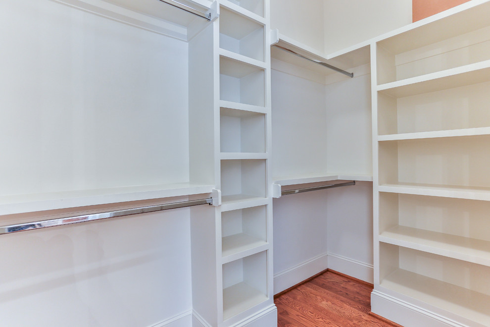 Ejemplo de armario vestidor unisex clásico de tamaño medio con armarios abiertos, puertas de armario blancas y suelo de madera en tonos medios
