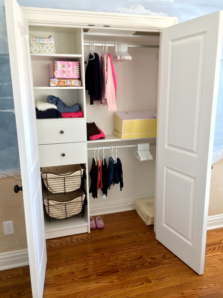 Reach-in closet - traditional medium tone wood floor reach-in closet idea in New York with flat-panel cabinets and white cabinets