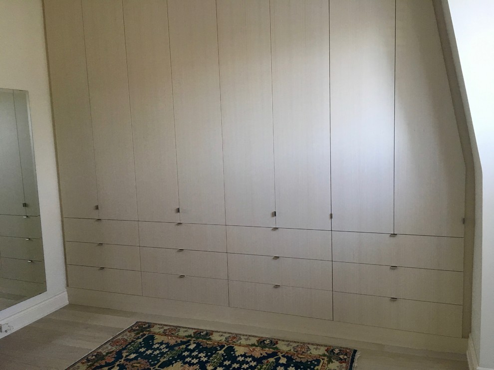 Foto de armario contemporáneo con armarios con paneles lisos, puertas de armario de madera clara y suelo de madera clara