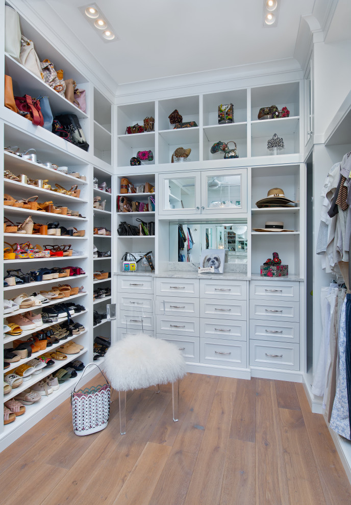 Ejemplo de armario vestidor de mujer mediterráneo con armarios abiertos, puertas de armario blancas y suelo de madera en tonos medios