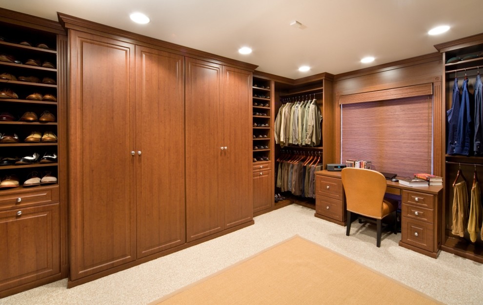 Пример оригинального дизайна: огромная гардеробная комната унисекс в классическом стиле с фасадами с выступающей филенкой, фасадами цвета дерева среднего тона и ковровым покрытием