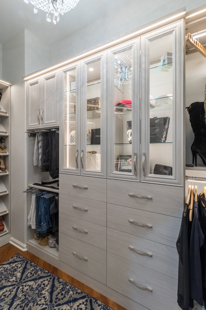 Inspiration for a medium sized traditional walk-in wardrobe for women in Minneapolis with glass-front cabinets, light wood cabinets and medium hardwood flooring.