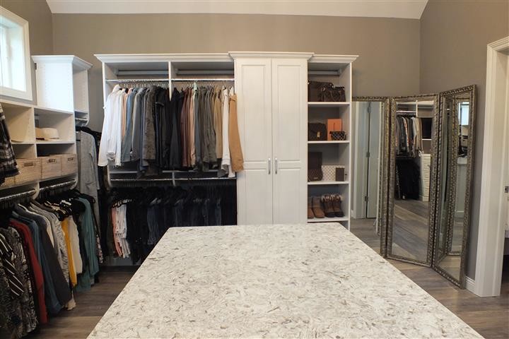 Ejemplo de armario vestidor unisex contemporáneo extra grande con armarios con paneles con relieve, puertas de armario blancas, suelo vinílico y suelo marrón
