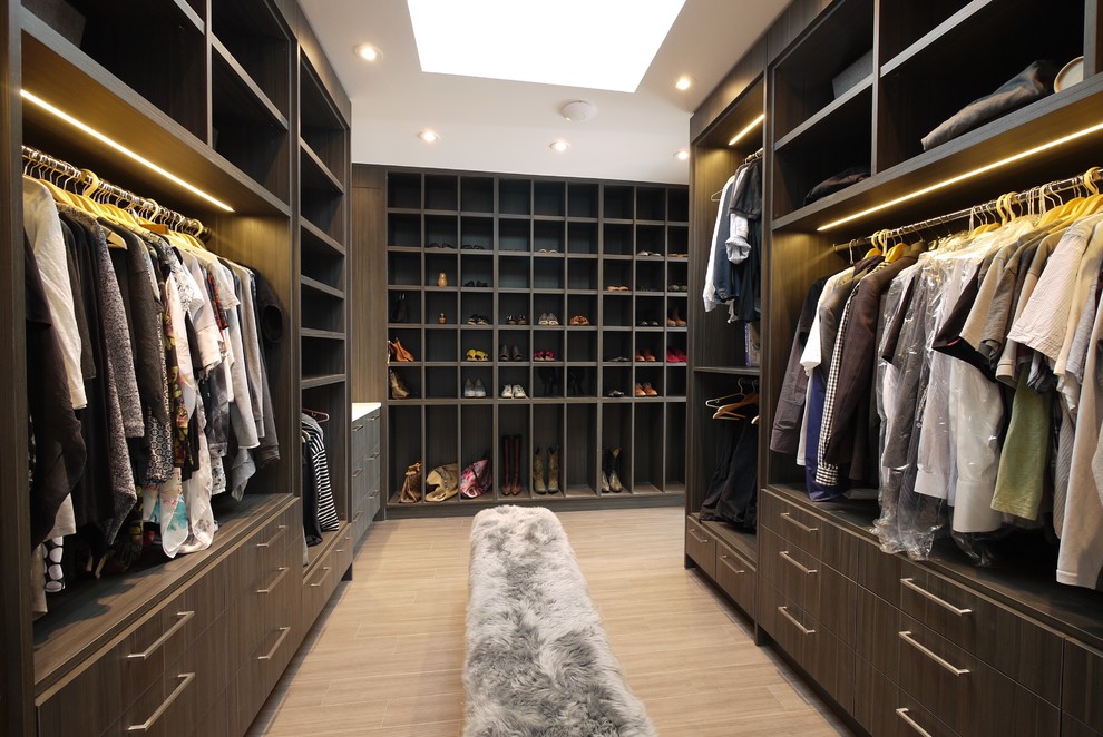 Imagen de vestidor unisex contemporáneo grande con armarios con paneles lisos, puertas de armario de madera en tonos medios, suelo beige y suelo de madera clara