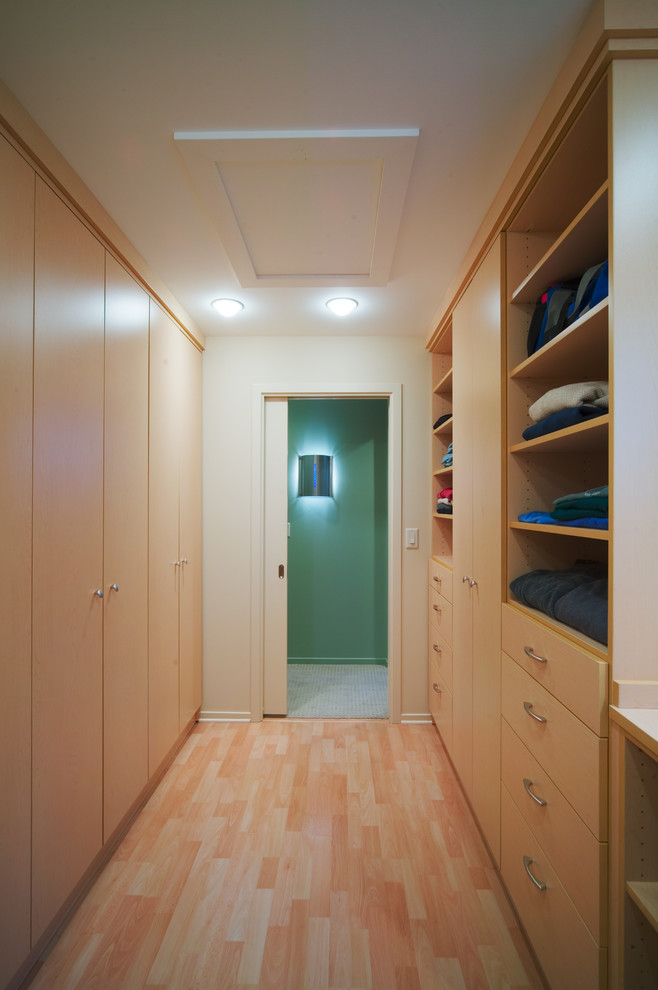 This is an example of a contemporary walk-in wardrobe in Detroit with light wood cabinets.
