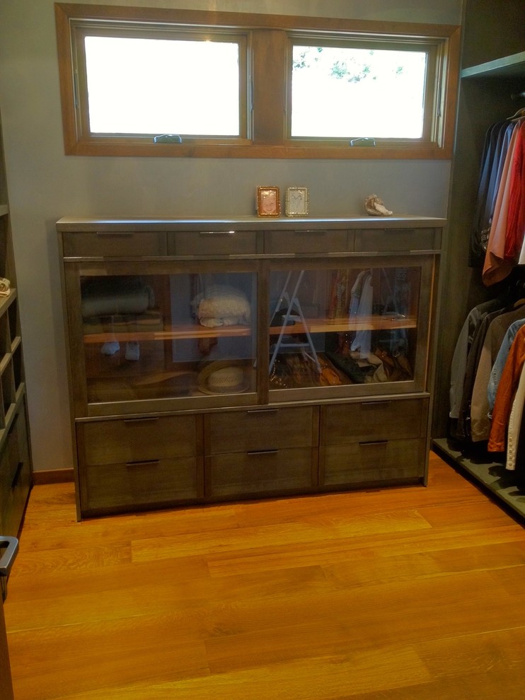 Medium sized industrial walk-in wardrobe for women in Los Angeles with recessed-panel cabinets and dark wood cabinets.